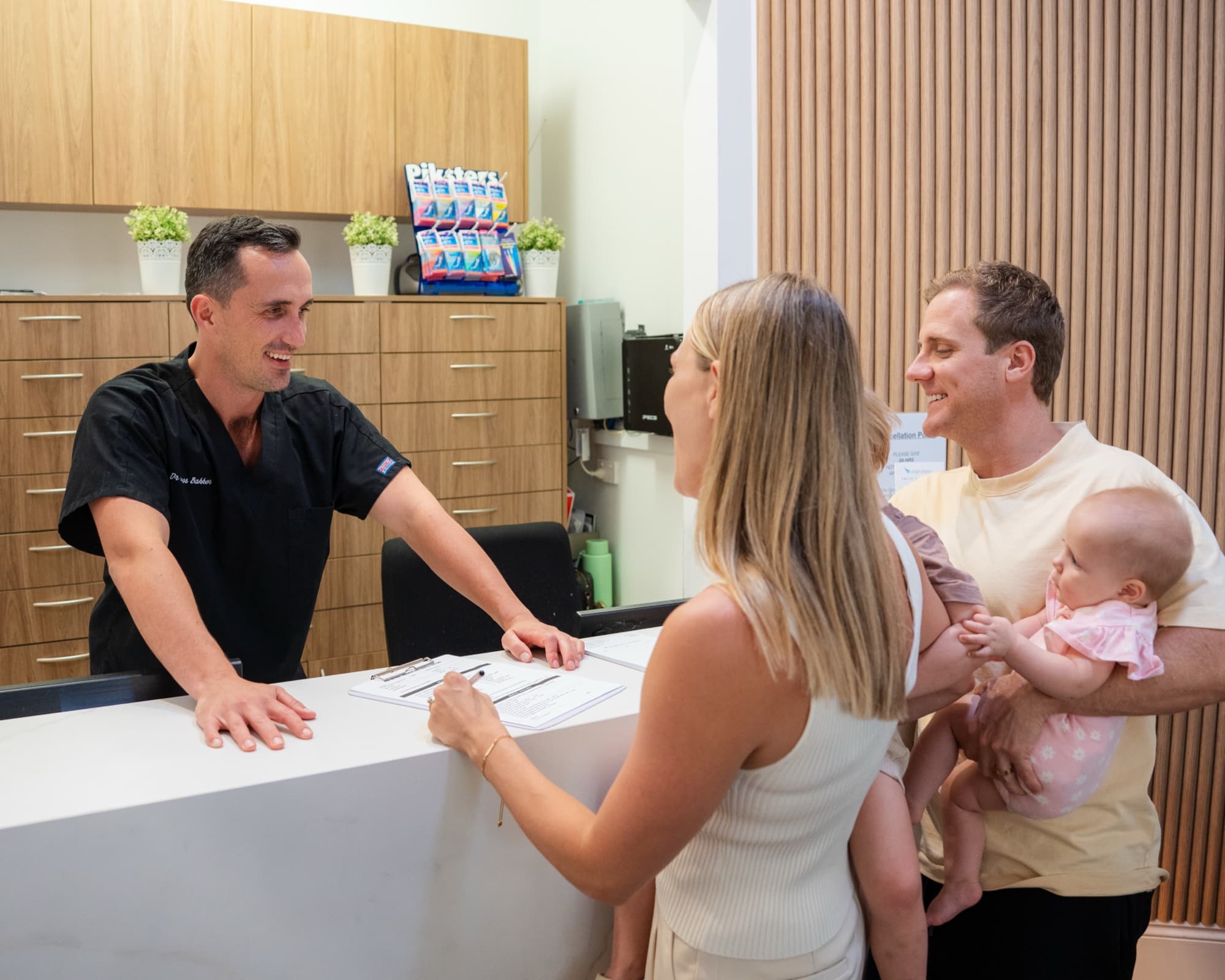 Dr James Bakker welcoming a family with their baby at the reception desk